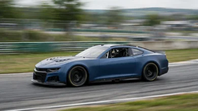 Blue NASCAR stock car speeding around a racetrack