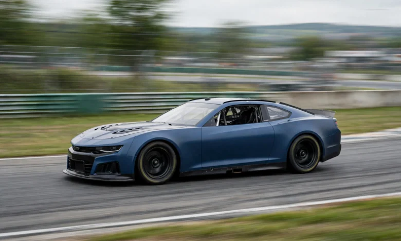 Blue NASCAR stock car speeding around a racetrack